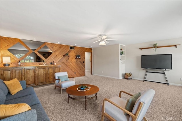 living room with wooden walls, ceiling fan, and light colored carpet