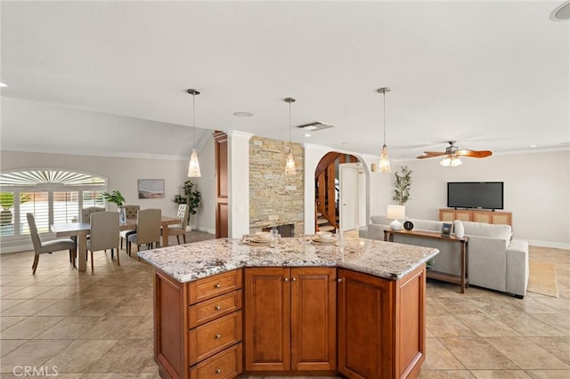 kitchen with light stone countertops, ceiling fan, pendant lighting, and a center island