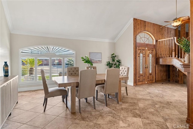 dining space featuring vaulted ceiling, ceiling fan, wooden walls, and crown molding