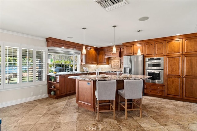 kitchen featuring a kitchen bar, light stone countertops, a center island with sink, pendant lighting, and appliances with stainless steel finishes