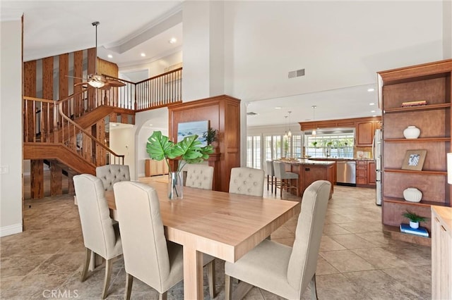 dining room with a towering ceiling, light tile patterned flooring, and ceiling fan