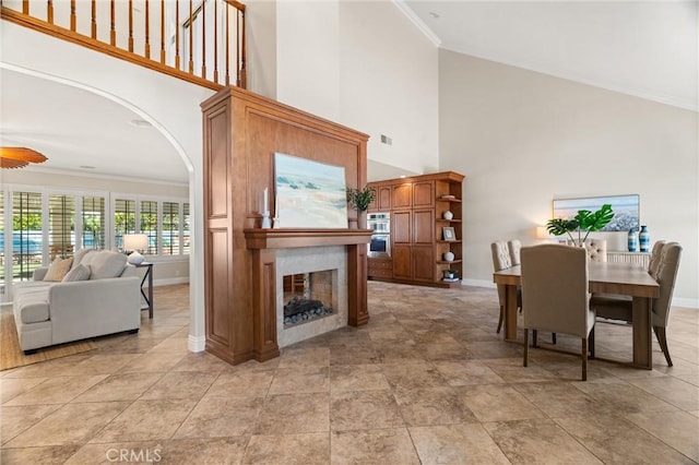 dining room featuring a high ceiling, a fireplace, and crown molding