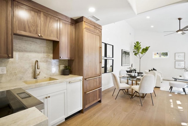 kitchen with sink, light wood-type flooring, ceiling fan, decorative backsplash, and white cabinets