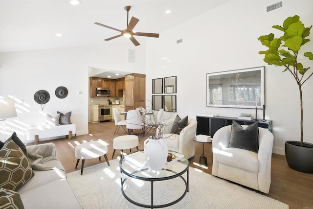 living room with ceiling fan, high vaulted ceiling, and light hardwood / wood-style floors