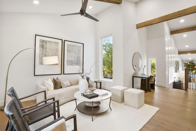 living room featuring a healthy amount of sunlight, beam ceiling, and light wood-type flooring