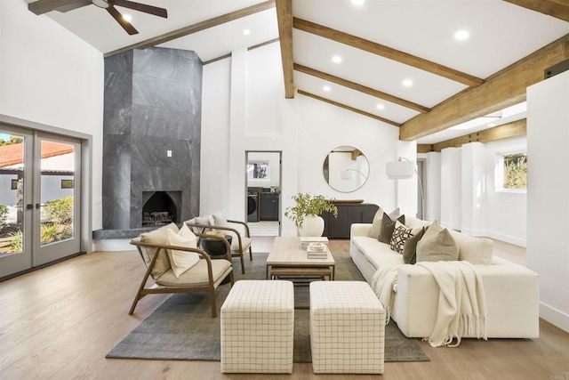 living room featuring beamed ceiling, high vaulted ceiling, washing machine and dryer, and light wood-type flooring