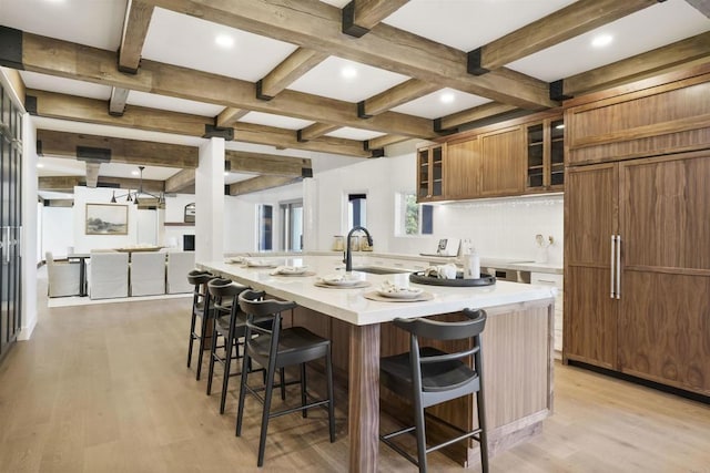 kitchen with a spacious island, light wood-type flooring, beamed ceiling, and a kitchen bar