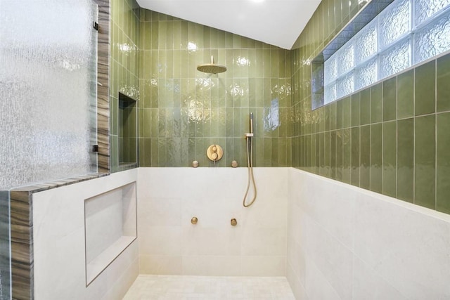 bathroom featuring lofted ceiling and tiled shower