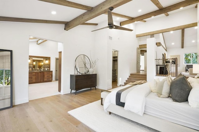 bedroom with connected bathroom, a spacious closet, light hardwood / wood-style flooring, and lofted ceiling with beams