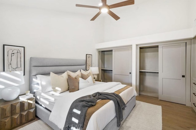 bedroom featuring two closets, ceiling fan, and light wood-type flooring