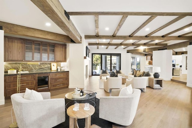 living room featuring sink, beam ceiling, wine cooler, light hardwood / wood-style floors, and french doors