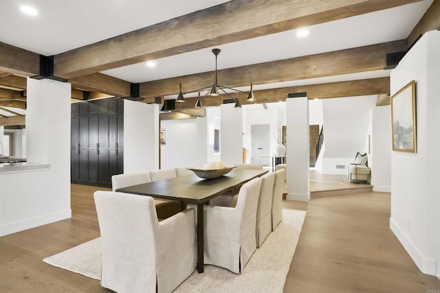 dining area featuring beam ceiling and light hardwood / wood-style floors