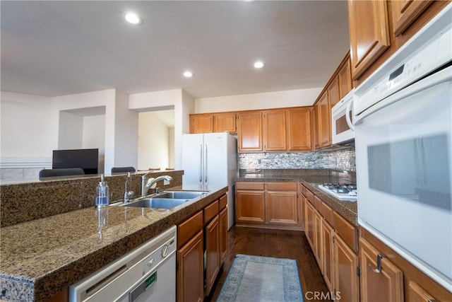 kitchen with decorative backsplash, dark hardwood / wood-style floors, sink, and white appliances