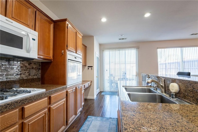 kitchen featuring sink, backsplash, dark hardwood / wood-style floors, and white appliances