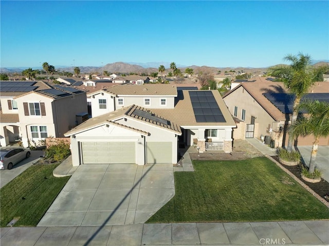 view of front facade featuring a front yard, a garage, a mountain view, and solar panels