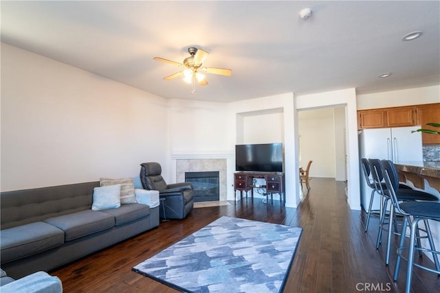 living room featuring ceiling fan, dark hardwood / wood-style floors, and a tile fireplace