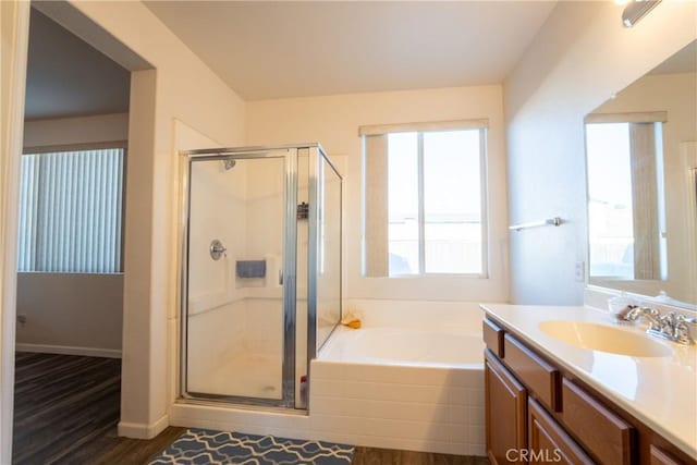 bathroom with wood-type flooring, vanity, and plus walk in shower