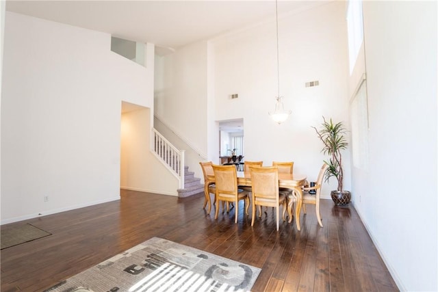 dining room with a high ceiling and dark hardwood / wood-style floors