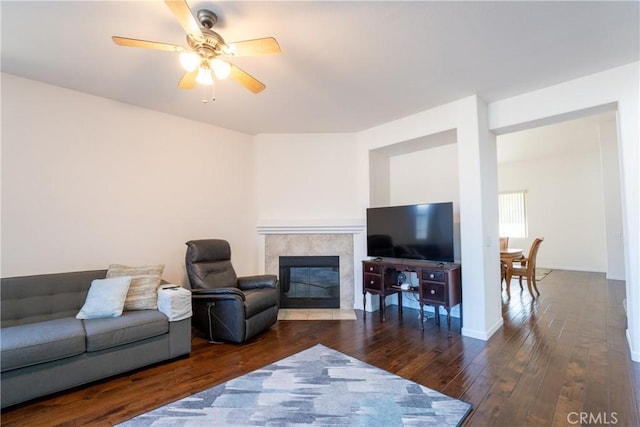 living room featuring ceiling fan, dark wood-type flooring, and a fireplace