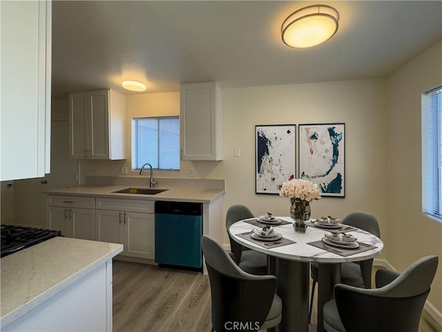 kitchen featuring sink, stainless steel dishwasher, light wood-type flooring, and white cabinetry