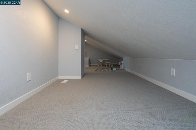 additional living space featuring carpet flooring and vaulted ceiling