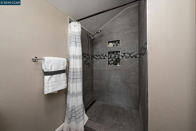 bathroom featuring lofted ceiling, a shower with shower curtain, and a textured ceiling