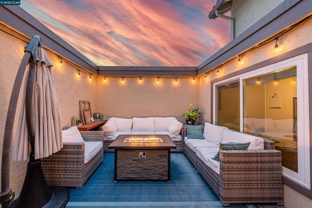 patio terrace at dusk with an outdoor living space with a fire pit and a deck