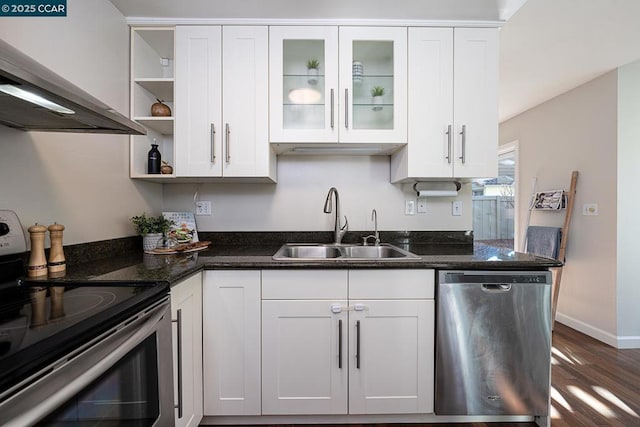 kitchen with stainless steel appliances, sink, white cabinets, wall chimney exhaust hood, and dark stone countertops