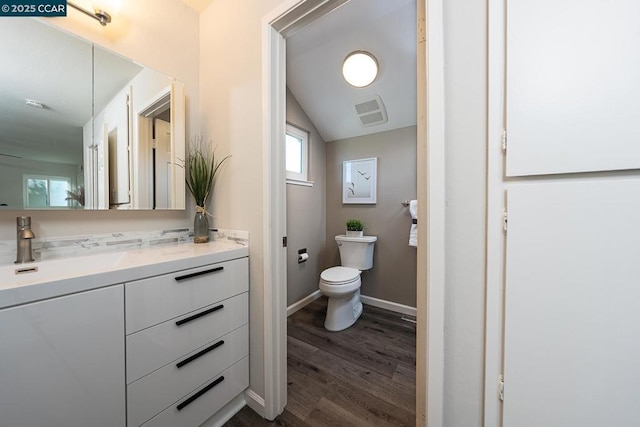 bathroom with vaulted ceiling, toilet, vanity, and hardwood / wood-style flooring