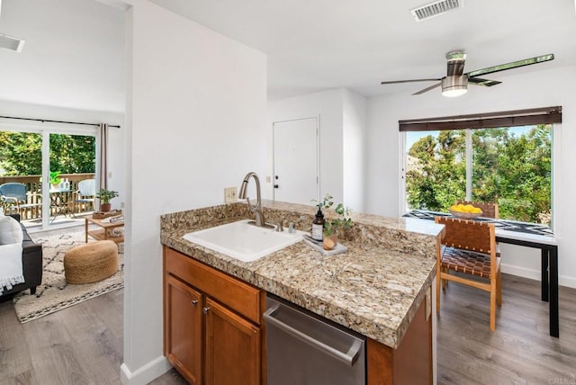 kitchen with light hardwood / wood-style floors, ceiling fan, dishwasher, light stone countertops, and sink