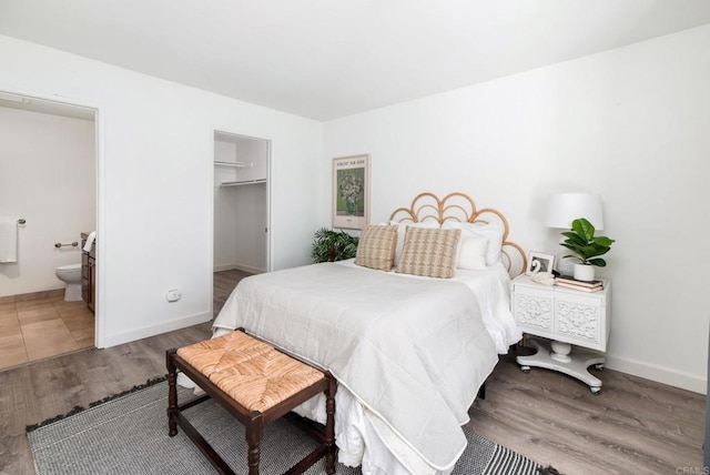 bedroom featuring a closet, a spacious closet, connected bathroom, and hardwood / wood-style flooring