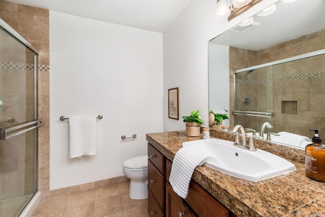 bathroom featuring a shower with shower door, toilet, vanity, and tile patterned flooring