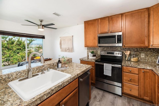 kitchen featuring decorative backsplash, sink, appliances with stainless steel finishes, and light hardwood / wood-style flooring