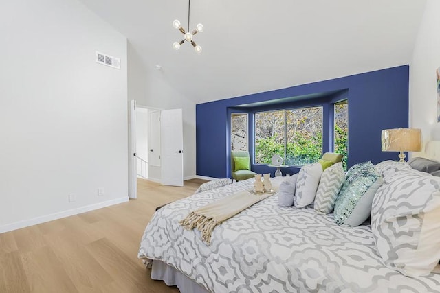 bedroom featuring high vaulted ceiling, an inviting chandelier, and light hardwood / wood-style floors