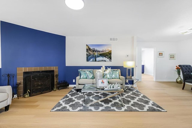 living room with a tiled fireplace and hardwood / wood-style floors