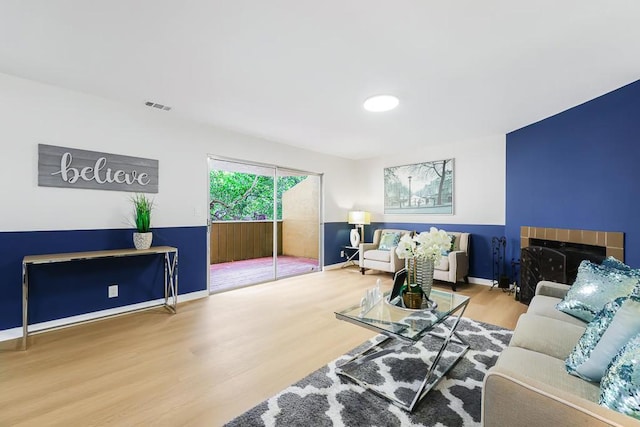 living room with a tile fireplace and hardwood / wood-style floors