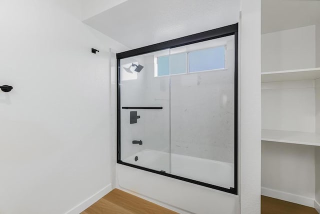 bathroom featuring hardwood / wood-style floors and shower / bath combination with glass door