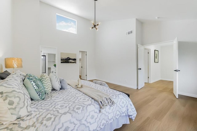 bedroom featuring a towering ceiling and light hardwood / wood-style floors