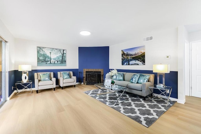 living room with a tile fireplace and wood-type flooring