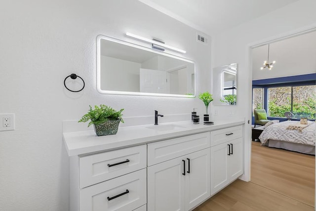 bathroom featuring an inviting chandelier, wood-type flooring, and vanity