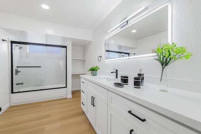 bathroom featuring shower / bath combination with glass door, hardwood / wood-style flooring, and vanity