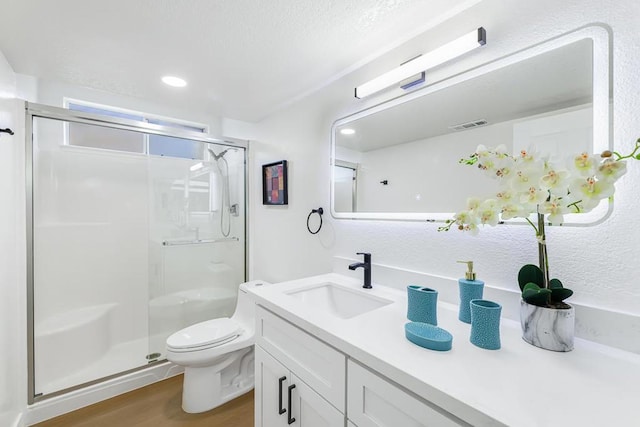 bathroom with toilet, hardwood / wood-style flooring, a shower with door, and vanity