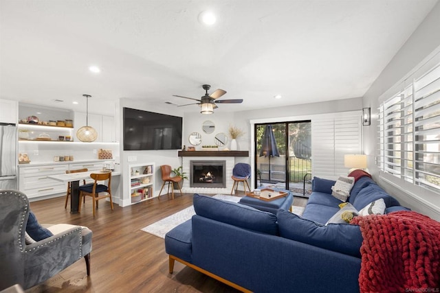 living room with ceiling fan, dark wood-type flooring, and a fireplace