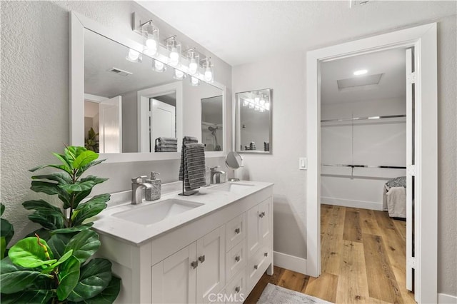 full bathroom with double vanity, baseboards, a sink, and wood finished floors