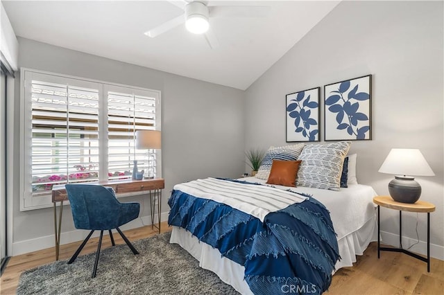 bedroom with a ceiling fan, baseboards, vaulted ceiling, and wood finished floors