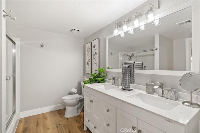 bathroom with wood finished floors, a stall shower, a sink, and visible vents