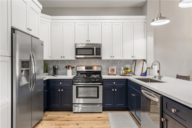 kitchen featuring light wood-style floors, tasteful backsplash, appliances with stainless steel finishes, and a sink