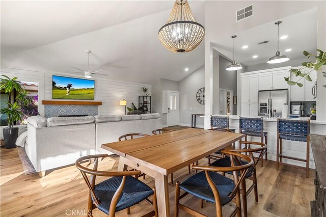 dining room featuring ceiling fan with notable chandelier, high vaulted ceiling, light wood-style flooring, and visible vents