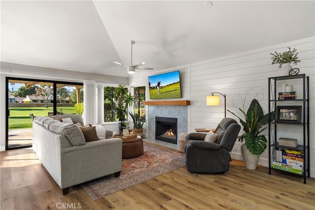 living room featuring a ceiling fan, lofted ceiling, a fireplace, and wood finished floors