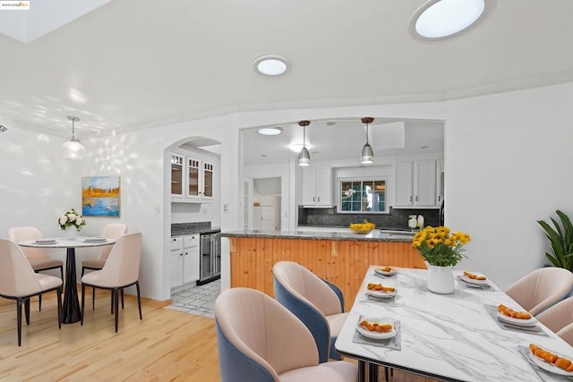 dining space with wine cooler and light hardwood / wood-style floors